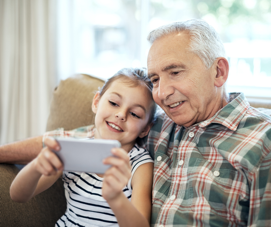 A child and grandfather using a phone