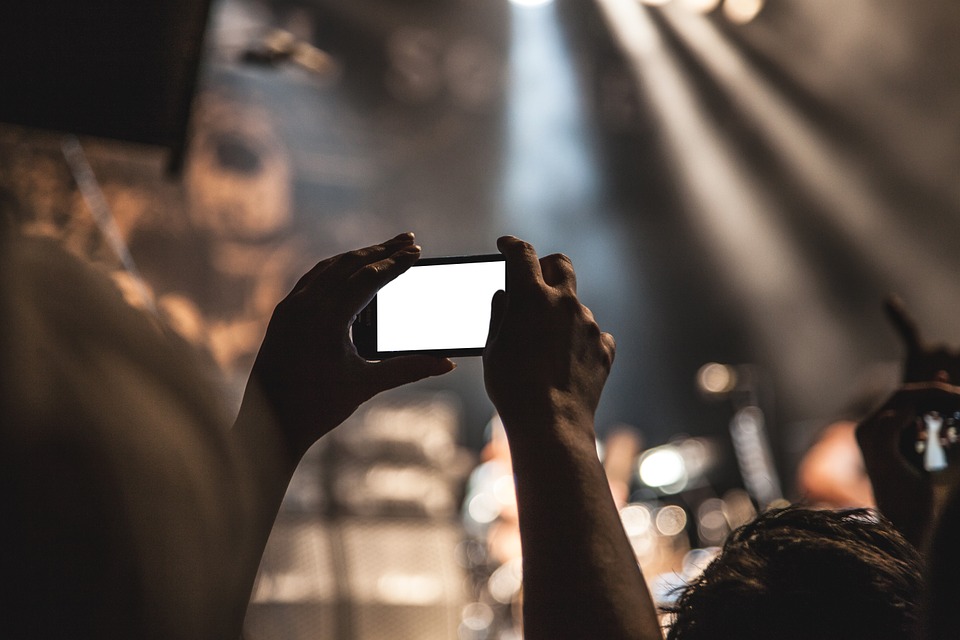 Someone using a smartphone camera at a concert
