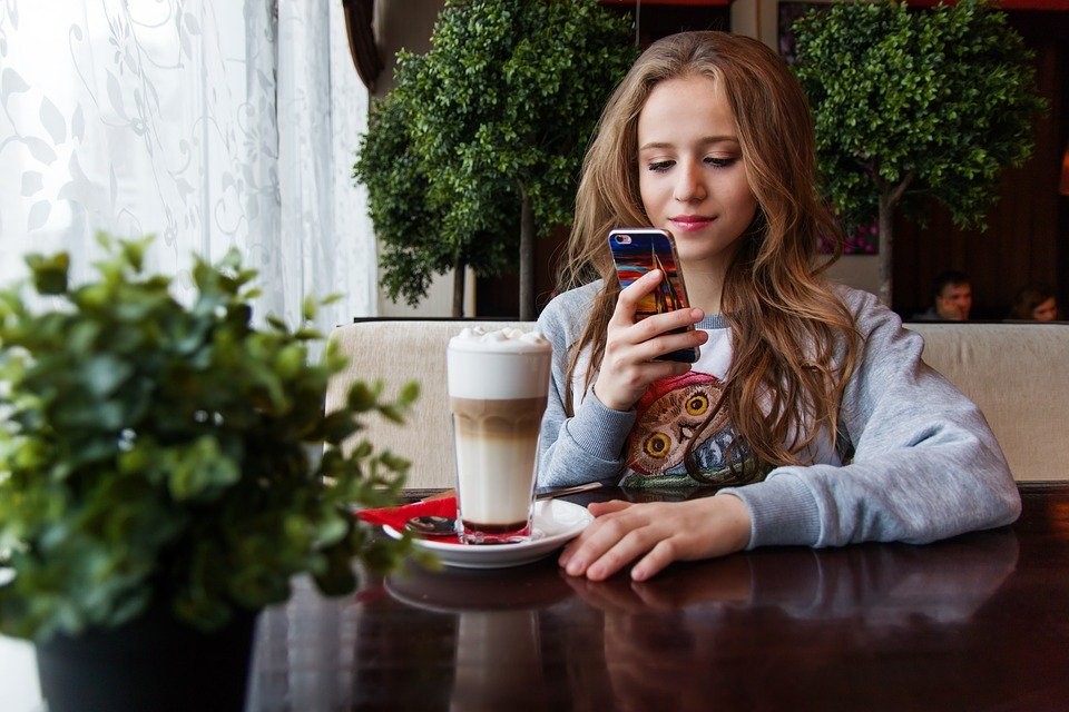 girl using a phone in a coffee shop