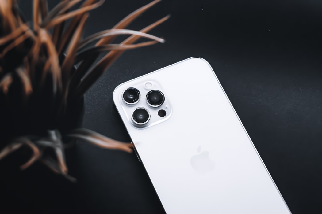 A white iPhone 12 Pro Max next to a plant