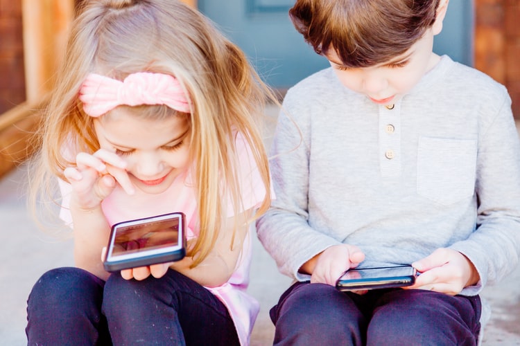 Two children playing on phones