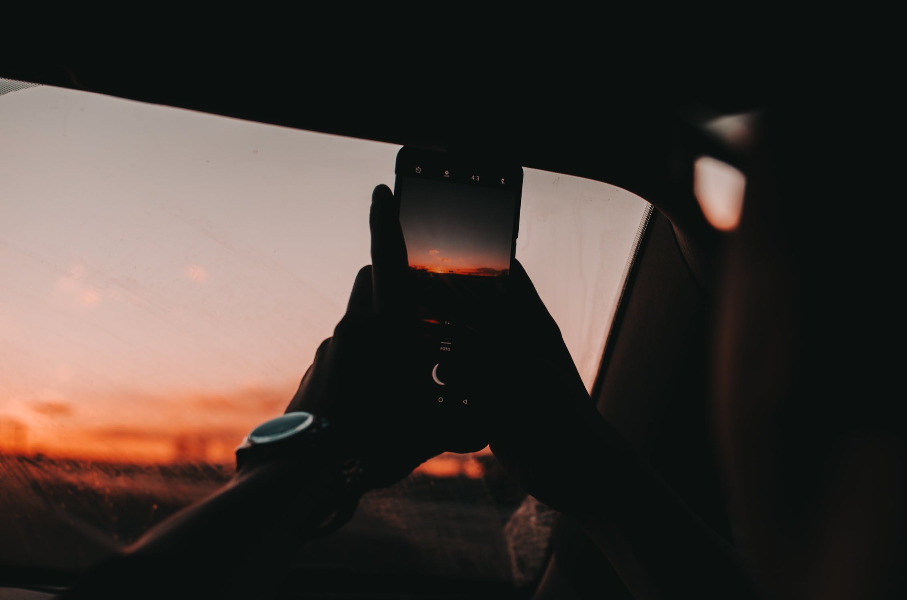 Someone taking a picture of the sunset on their phone